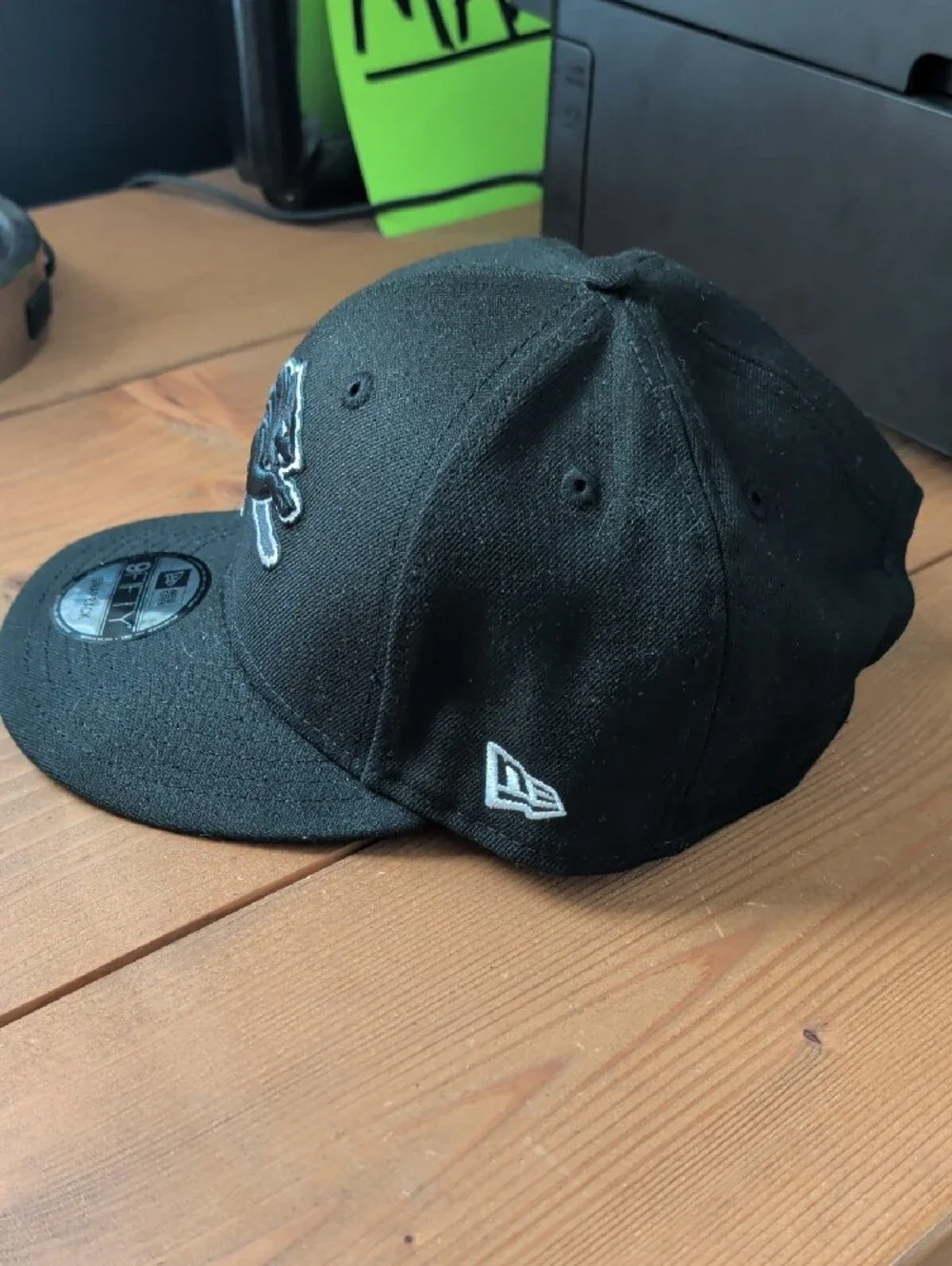 New Era Black Snapback Hat with Gray-Outlined Lion Patch